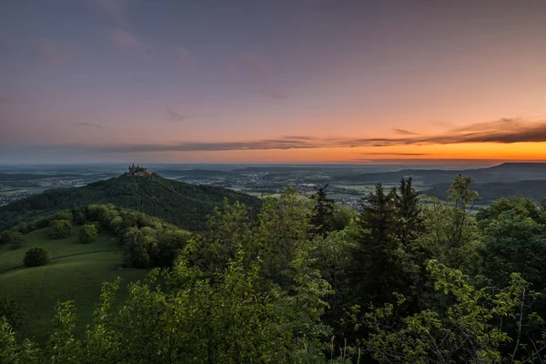 Sunrise at Zeller Horn with view to medieval knight castle Burg Hohenzollern with beautiful colored clouds in the sky in autumn in Bisingen Hechingen, Germany