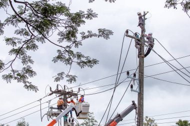 Elektrik direğindeki Taylandlı elektrikçiler kabloları tamir etmek için acele ediyorlar. Yağmur sezonundan önce Chiang Mai, Tayland, 6-11-2021 'deki elektrik kesintisini çözün.
