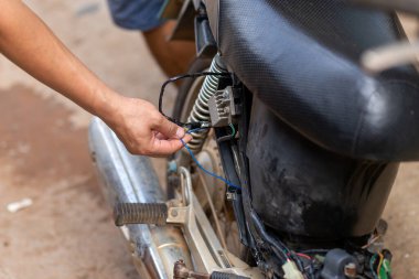 Motosiklet atölyesindeki elektrik sorunlu motorsikletlerin seçici odaklı elektrik kabloları denetlenecek.