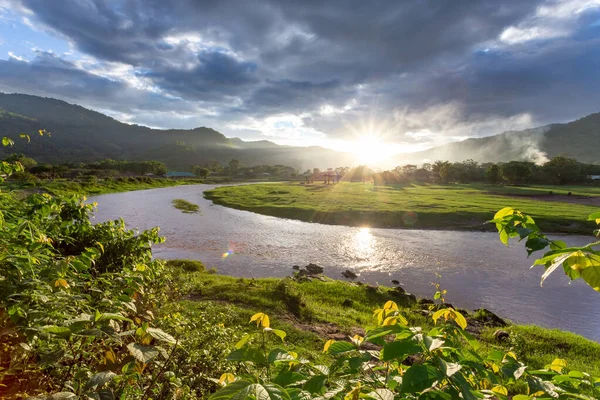 Manzara, nehir kıvrılır, dağlar, gökyüzü, gün batımı sıcaklık ve tazelik hissi verir. Doğal arka plan tasarımı için yeşil çayır hayvancılık alanı Tayland Hayvan Çiftliği