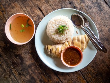 Tavuklu pilav, Tayland yemeği, yüksek açılı pirinç ve ahşap bir masada yüksek açılı beyaz tabakta haşlanmış tavuk var. Metin için boşluk var.