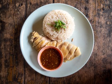 Tavuklu pilav, Tayland yemeği, yüksek açılı pirinç ve ahşap bir masada yüksek açılı beyaz tabakta haşlanmış tavuk var. Metin için boşluk var.