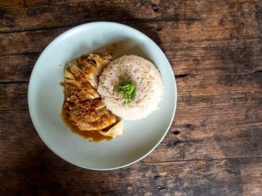 Tavuklu pilav, Tayland yemeği, yüksek açılı pirinç ve ahşap bir masada yüksek açılı beyaz tabakta haşlanmış tavuk var. Metin için boşluk var.