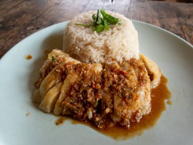 Tavuklu pilav, Tayland yemeği, yüksek açılı pirinç ve ahşap bir masada yüksek açılı beyaz tabakta haşlanmış tavuk var. Metin için boşluk var.
