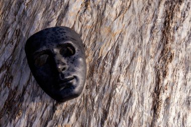 Seçici odaklı siyah plastik maske güzel desenli bir taşın üzerine yerleştirilmiş. Güçlü bir his verir ve karanlık güçler kavramına sahiptir. İnsanın karanlık tarafı. Metin için yer vardır..