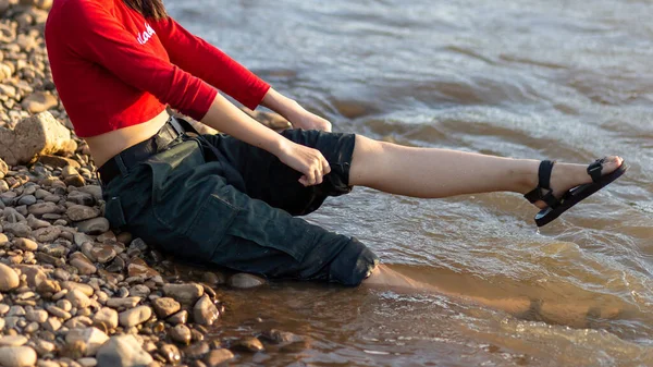 Asian woman folding her pants Sit with your legs in the water and relax by the river. woman wearing red shirt wet pants