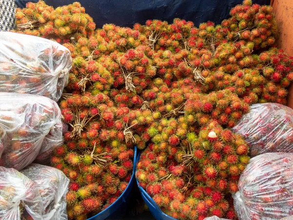 a pile of rambutan in the basket and plastic bags on the back of the fruit truck in the market Fruits from Thai garden in rainy season Rambutan in the fresh fruit market