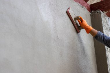 Çimento duvarı sıvanmış. Tecrübeli teknisyenler binanın duvarına sıva yapıyor. Metin için yer bırakın..