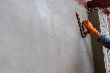 Çimento duvarı sıvanmış. Tecrübeli teknisyenler binanın duvarına sıva yapıyor. Metin için yer bırakın..