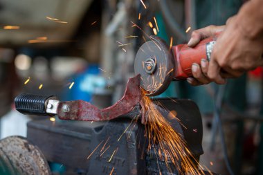 Genç işçiler metal öğütücüleri kullanır. Metal öğütücüden güzel turuncu parıltılar tasarlamak ve modifiye etmek için bir motosikletin çelik parçalarını..