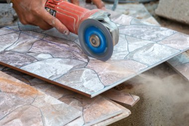 Kapalı zemin fayansları inşaatçılar tarafından elektrik kesici ile kesiliyor..