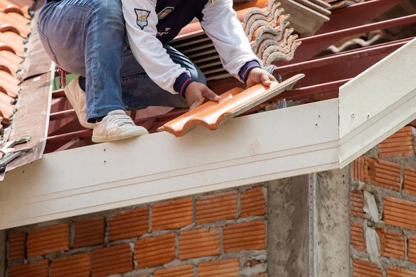 Yeni turuncu çatı kiremitleri, kalın plan, inşaatçılar tarafından çatıda monte ediliyor. Bu çok tehlikeli bir iş. Tayland 'da inşaat işinde çalışan yetenekli teknisyenler tarafından.