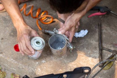 Sprey tabanca elinde bir şey tutuyordu..