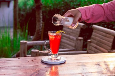 Temiz bir bardaktaki çilek içeceği bir kadın eliyle yoğurtla karıştırılmak üzere..