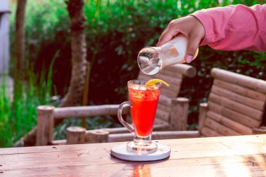 Temiz bir bardaktaki çilek içeceği bir kadın eliyle yoğurtla karıştırılmak üzere..