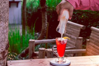 Temiz bir bardaktaki çilek içeceği bir kadın eliyle yoğurtla karıştırılmak üzere..