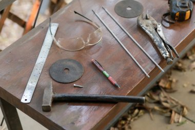 Kesici bıçak, yüksek açılı demir ve el aletleri tozlu ahşap bir masaya yerleştirilmiş..