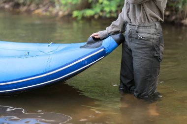 Mavi lastik bir tekneyi kıyıya çeken bir kadının yakın çekimi..
