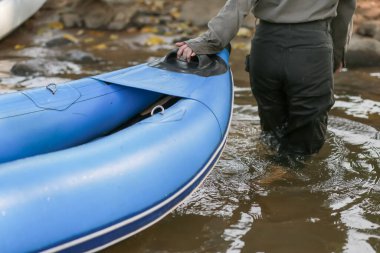 Mavi lastik bir tekneyi kıyıya çeken bir kadının yakın çekimi..