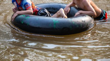 Nehirde oynayan çocuklarla birlikte siyah lastik halkayı kapatın. Tayland 'ın sıcak havasında aile tatili aktivitesi. Çocuklar mutlu ve rahatlar. Nehirde lastik halka