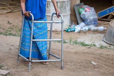 Yürüme iskeleti kullanan yaşlı bir kadın eli, Tayland 'ın kırsal kesimlerinde yaşlı bir büyükanneyle yürüyen bir yardım..