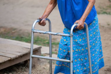 Yürüme iskeleti kullanan yaşlı bir kadın eli, Tayland 'ın kırsal kesimlerinde yaşlı bir büyükanneyle yürüyen bir yardım..