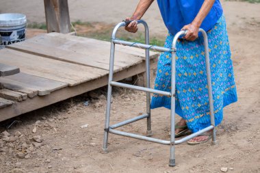 Yürüme iskeleti kullanan yaşlı bir kadın eli, Tayland 'ın kırsal kesimlerinde yaşlı bir büyükanneyle yürüyen bir yardım..