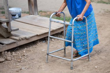 Yürüme iskeleti kullanan yaşlı bir kadın eli, Tayland 'ın kırsal kesimlerinde yaşlı bir büyükanneyle yürüyen bir yardım..