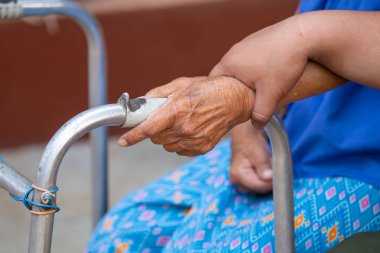 Yürüme iskeleti kullanan yaşlı bir kadın eli, Tayland 'ın kırsal kesimlerinde yaşlı bir büyükanneyle yürüyen bir yardım..