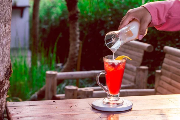 Temiz bir bardaktaki çilek içeceği bir kadın eliyle yoğurtla karıştırılmak üzere..