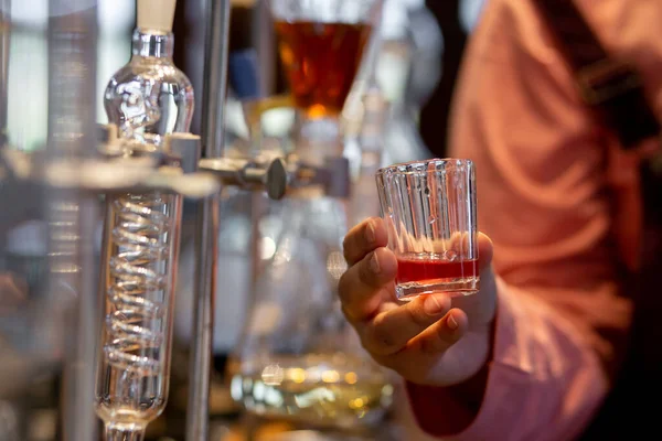 Laboratuvardaki kadının elinde, temiz, damıtılmış bir bardakta meyve suyu yakın plan çekimi.