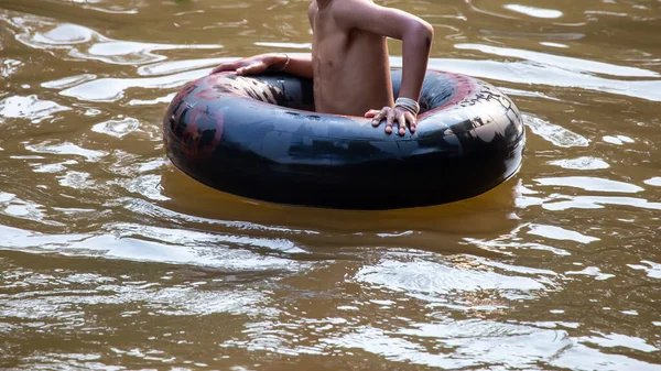 Nehirde oynayan çocuklarla birlikte siyah lastik halkayı kapatın. Tayland 'ın sıcak havasında aile tatili aktivitesi. Çocuklar mutlu ve rahatlar. Nehirde lastik halka