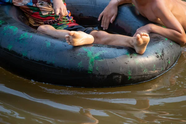 Nehirde oynayan çocuklarla birlikte siyah lastik halkayı kapatın. Tayland 'ın sıcak havasında aile tatili aktivitesi. Çocuklar mutlu ve rahatlar. Nehirde lastik halka