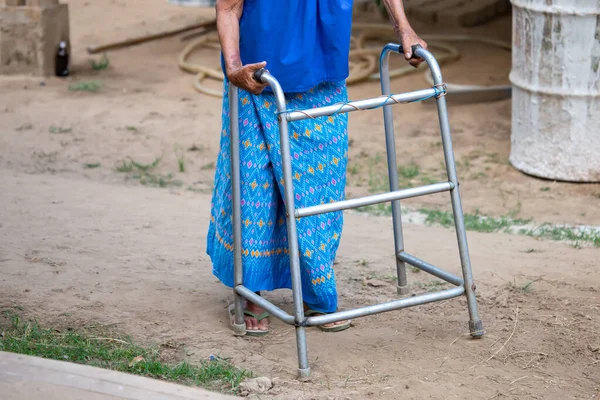 Yürüme iskeleti kullanan yaşlı bir kadın eli, Tayland 'ın kırsal kesimlerinde yaşlı bir büyükanneyle yürüyen bir yardım..