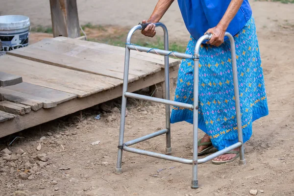 Yürüme iskeleti kullanan yaşlı bir kadın eli, Tayland 'ın kırsal kesimlerinde yaşlı bir büyükanneyle yürüyen bir yardım..
