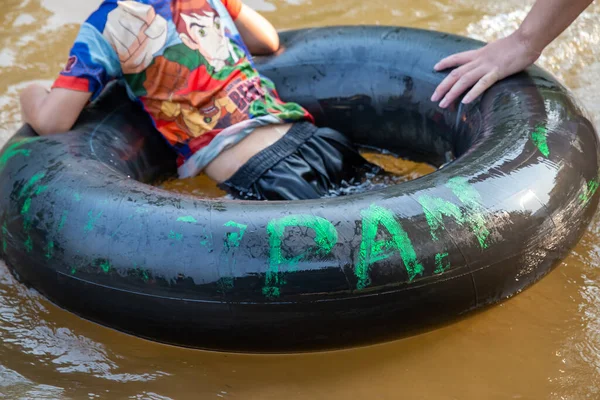 Nehirde oynayan çocuklarla birlikte siyah lastik halkayı kapatın. Tayland 'ın sıcak havasında aile tatili aktivitesi. Çocuklar mutlu ve rahatlar. Nehirde lastik halka
