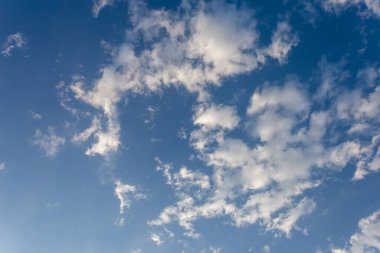 Yüzen bir sürü güzel beyaz bulut ve bulutların arasında parlayan parlak mavi gökyüzü var. Mavi arkaplan tasarımı için gökyüzü görüntüleri sizi taze ve parlak hissettirir.