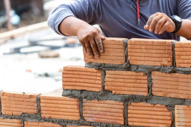 Duvarcı eliyle turuncu tuğlaları kapatıyoruz evin duvarlarını inşa ediyoruz, duvarları oluşturmak için tuğla dizayn ediyoruz.