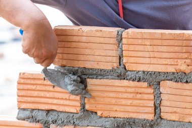 Duvarcı eliyle turuncu tuğlaları kapatıyoruz evin duvarlarını inşa ediyoruz, duvarları oluşturmak için tuğla dizayn ediyoruz.
