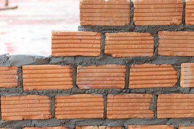 Turuncu tuğlalardan oluşan bir duvar örüyoruz. Evin duvarlarını inşa ediyoruz. Duvarları oluşturmak için tuğla dizayn ediyoruz.