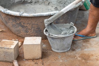 Yakın plan inşaat işçileri havanı küçük bir kovayla kürekle karıştırıyorlar..