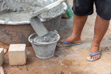 Yakın plan inşaat işçileri havanı küçük bir kovayla kürekle karıştırıyorlar..