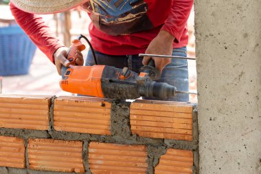 İnşaat işçileri tuğlaları örmek için inşaat demiri yerleştirmek için sütun yumruklama makineleri kullanıyorlar..