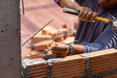 İnşaat işçileri tuğla duvarın istikrarını artırmak için inşaat işçilerini beton kolonlara dönüştürüyor..