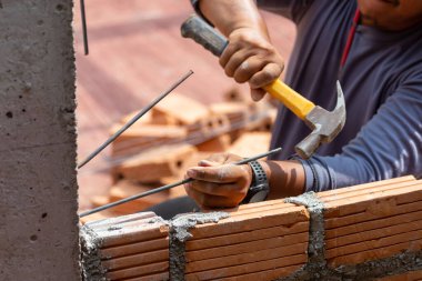İnşaat işçileri tuğla duvarın istikrarını artırmak için inşaat işçilerini beton kolonlara dönüştürüyor..