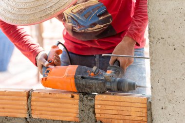 İnşaat işçileri tuğlaları örmek için inşaat demiri yerleştirmek için sütun yumruklama makineleri kullanıyorlar..