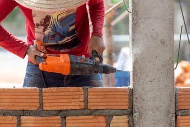 İnşaat işçileri tuğlaları örmek için inşaat demiri yerleştirmek için sütun yumruklama makineleri kullanıyorlar..