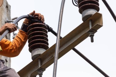 Elektrik direkleri elektrikçiler tarafından bağlanmak için kablo yerleştirilerek onarılıyor. Elektrik direklerinin üst kısmı yalıtıcıya bağlı. Yüksek faizli bir iş. Beyaz özgeçmişi var.