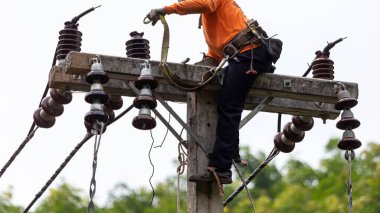 Elektrik direkleri elektrikçiler tarafından bağlanmak için kablo yerleştirilerek onarılıyor. Elektrik direklerinin üst kısmı yalıtıcıya bağlı. Yüksek faizli bir iş..