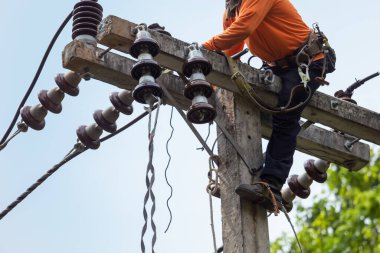 Elektrik direkleri elektrikçiler tarafından bağlanmak için kablo yerleştirilerek onarılıyor. Elektrik direklerinin üst kısmı yalıtıcıya bağlı. Yüksek faizli bir iş..